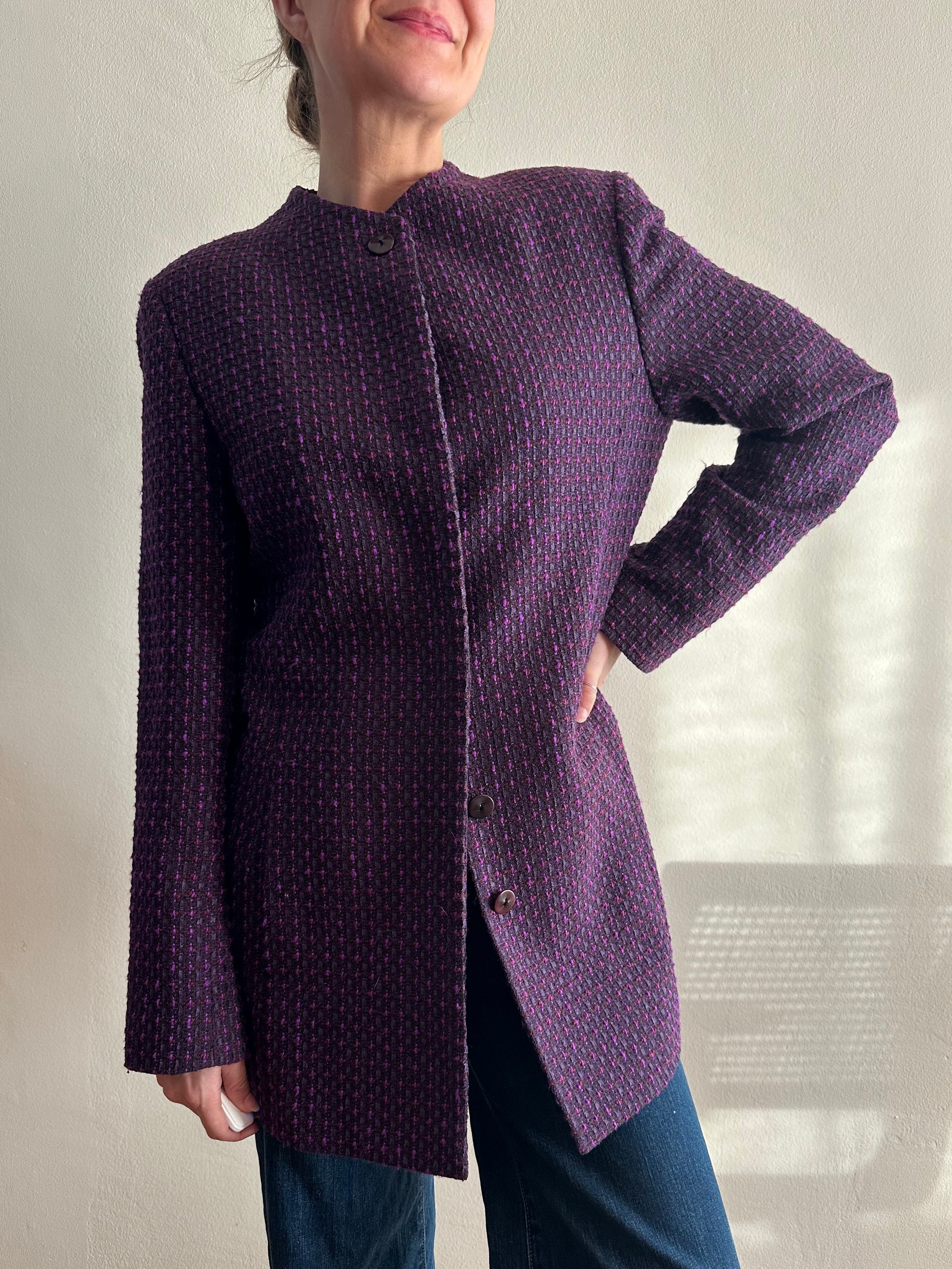 Person wearing a purple textured coat with a blurred indoor background