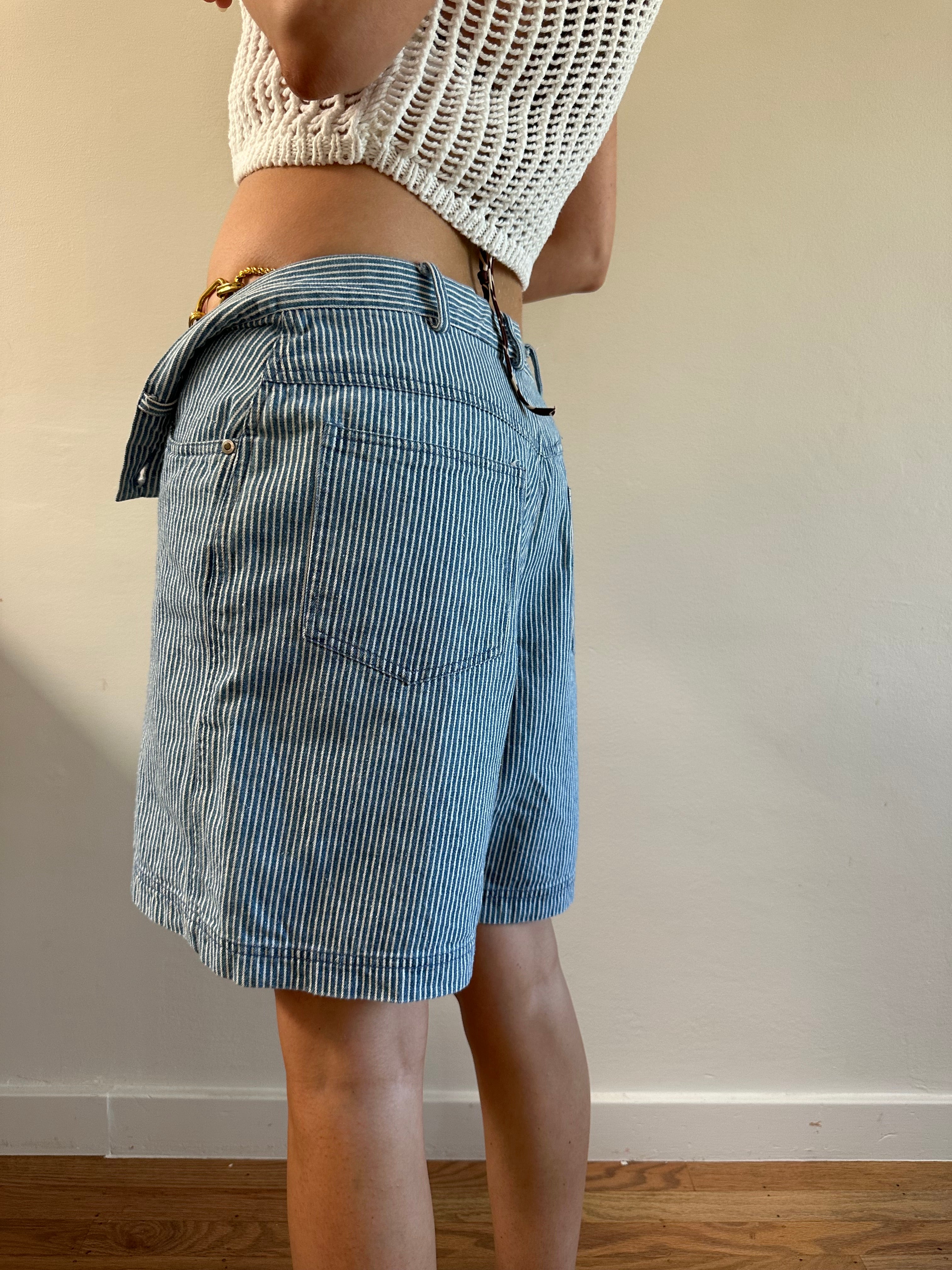 Person wearing blue striped shorts with a neutral background